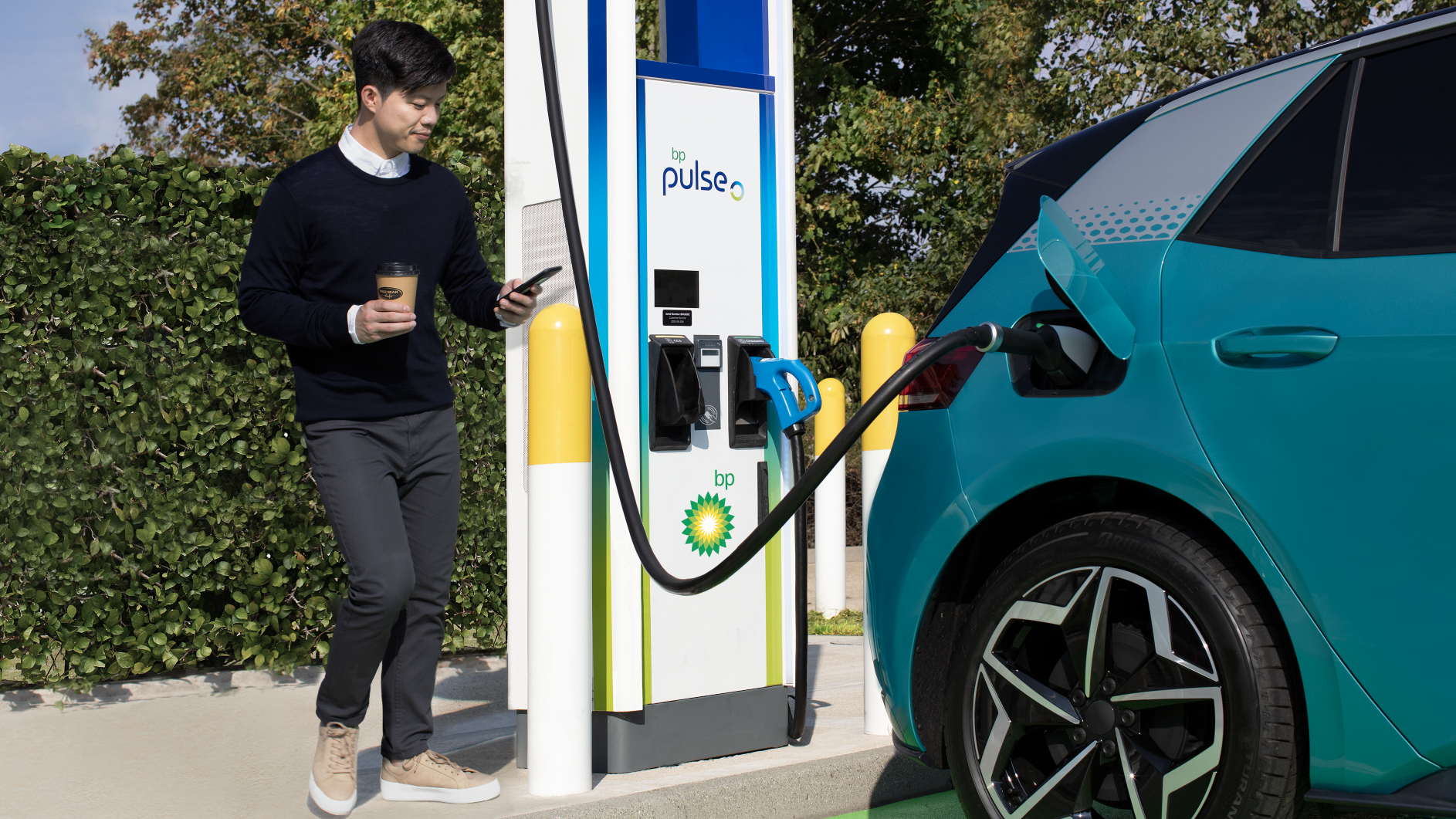 Electric Car Charging a Man looks at the App on his Smart Phone