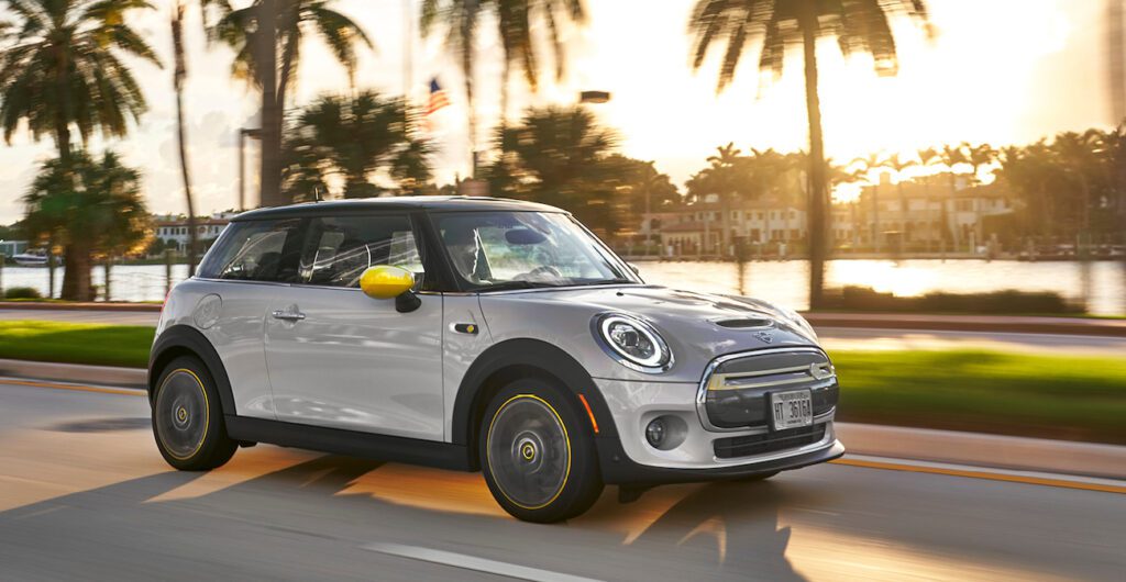 A grey Mini Electric driving along a waterfront