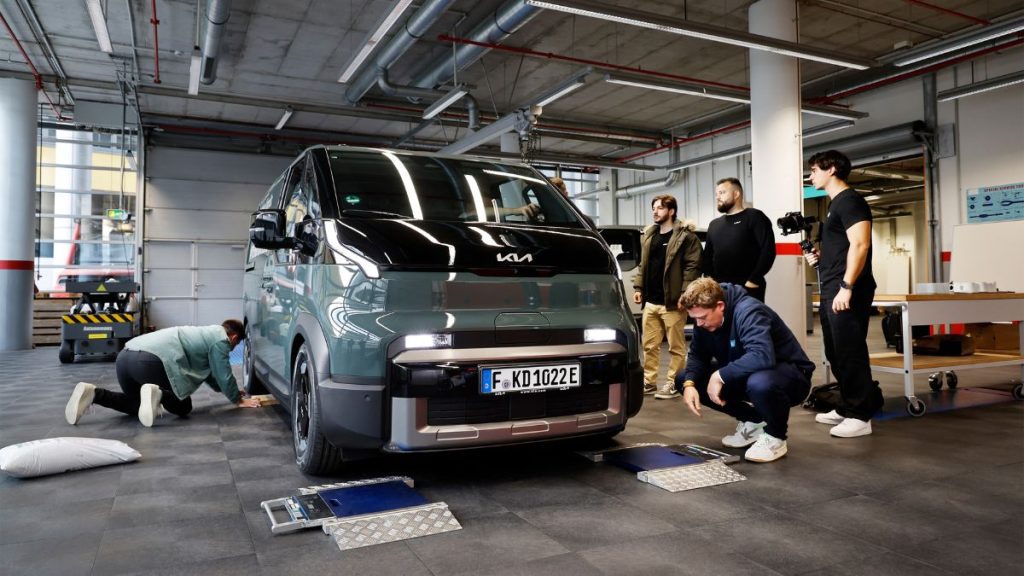 A Kia PV5 electric van standing on weight scales, with the total payload of the van being verified for the world record attempt.
